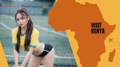 A young woman in a soccer jersey holding a football by a soccer goal