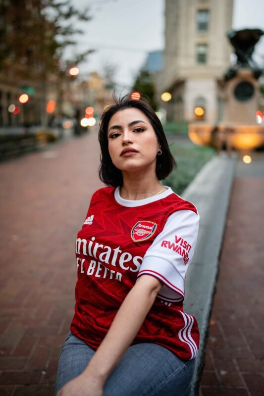 Photo of woman in an Arsenal FC jersey. Branded Visit Rwanda.