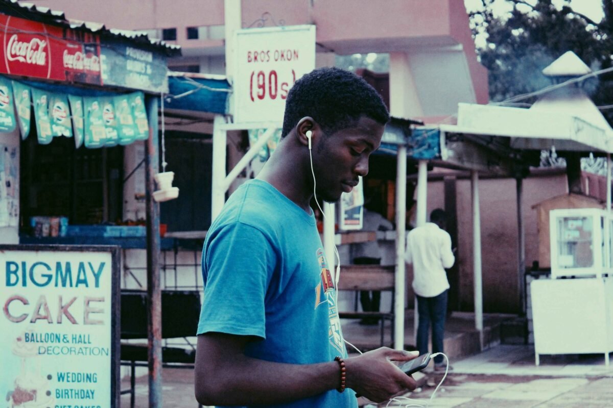 Photo of a young man listening to music on his phone on wired earphones